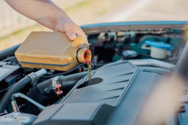 Bir arabanın motoruna motor yağı döken birinin yakın çekimi. Araç bakımı, yağ değişimi, otomotiv bakımı ve araba servisi kavramı.