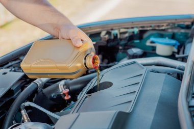 Bir arabanın motoruna motor yağı döken birinin yakın çekimi. Araç bakımı, yağ değişimi, otomotiv bakımı ve araba servisi kavramı.