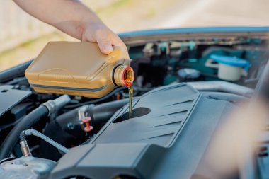 Bir arabanın motoruna motor yağı döken birinin yakın çekimi. Araç bakımı, yağ değişimi, otomotiv bakımı ve araba servisi kavramı.