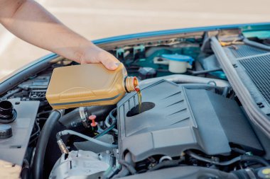 Bir arabanın motoruna motor yağı döken birinin yakın çekimi. Araç bakımı, yağ değişimi, otomotiv bakımı ve araba servisi kavramı.