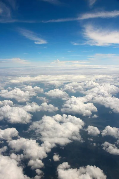 Fluffy clouds aerial view. Flying over white cumulus clouds - aircraft window view.