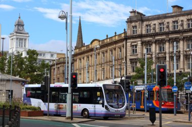 SHEFFIELD, İngiltere - 10 Temmuz 2016: İnsanlar Sheffield, Yorkshire, İngiltere 'de First City otobüsüne ve Posta Arabası Supertramvayına biniyor. Sheffield Supertram 2015 / 16 'da yılda 11,6 milyon yolculuk yaptı..