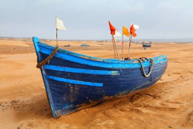 Fas manzarası. Essaouira sahilinin yakınındaki çölde mavi bir balıkçı teknesi..