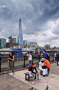 LONDON, İngiltere - 13 Temmuz 2019: Turistler Londra 'daki Thames Nehri setini ziyaret ederken, arka plandaki ufuk çizgisindeki Çömlek Ofisi binasını ziyaret ettiler.