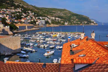 DUBROVNIK, CROATIA - JULY 18, 2021: Boat harbor in front of medieval Dubrovnik Old Town city walls, a UNESCO World Heritage Site.