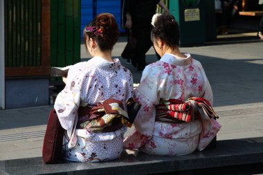 KYOTO, JAPONAN - 17 Nisan 2012: Geleneksel kimono kostümlü kadınlar Japonya 'nın Kyoto kentinde Arashiyama' yı ziyaret ederler. Arashiyama, ulusal olarak güzel ve tarihi bir mekan olarak belirlenmiştir..