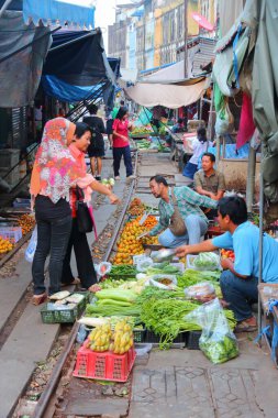 Samut Songkram, Tayland - 12 Aralık 2013: Satıcıları demiryolu parça Pazar Tayland Mae Klong yiyecek satmak. Piyasa etkin demiryolu hattı üzerindeki konumu için dikkat çekicidir.