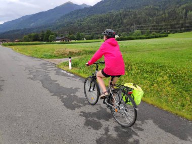 Avusturya, Carinthia 'da Gailradweg' de uzun mesafe bisiklet yolu üzerinde kask takan kadın bisikletçi..