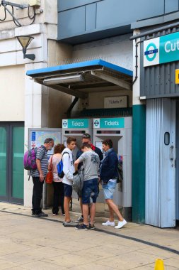 LONDON, İngiltere - 8 Temmuz 2016: Yolcular Londra, İngiltere 'deki bir bilet makinesinden Docklands Light Railway (DLR) biletleri satın alırlar. DLR yıllık 110.2 milyon turu sunuyor.