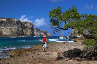 GUADELOUPE, FRANCE - DECEMBER 7, 2019: Woman tourist visits cliffs of Porte d'Enfer (Hell's Gate) in Guadeloupe. clipart