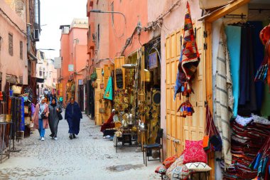 MARRAKESH, MOROCCO - FEBRUARY 20, 2022: People visit souk in medina (Old Town) of Marrakesh city, Morocco. The historic medina quarter is a UNESCO World Heritage Site. clipart