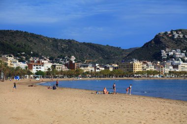 ROSES, SPAIN - 5 Ekim 2021: İnsanlar İspanya 'nın Kosta Brava tatil bölgesindeki Alt Emporda ilçesinin Roses kasabasındaki plajı ziyaret ediyor.