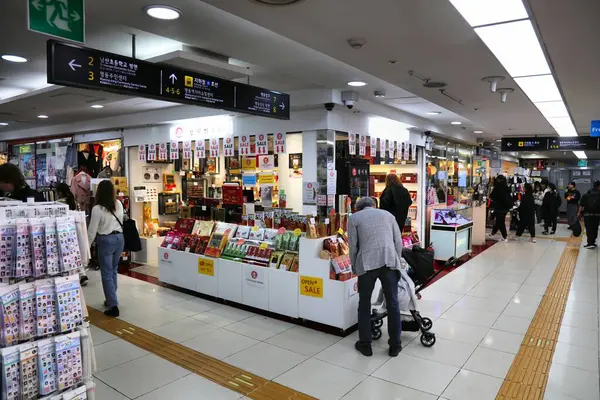 SEOUL, Güney Kore - 5 Nisan 2023: İnsanlar Myeongdong metro istasyonundaki yeraltı alışveriş merkezindeki hediyelik eşya dükkanını ziyaret ediyor.