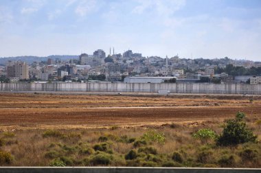Batı Şeria Bariyeri, İsrail ve Filistin topraklarını ayırıyor. Yitzhak Rabin otoyolu boyunca beton duvar var. Arka planda Kalkilya kasabası.