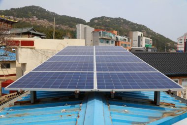 Küçük bir iş binasının çatısındaki güneş panelleri. Busan, Güney Kore 'de fotovoltaik enerji üretimi.