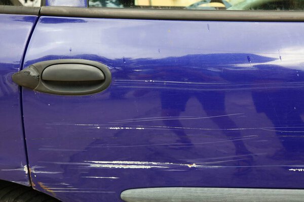 Car with scratched paint and dented parts on the side. Minor accident damage.
