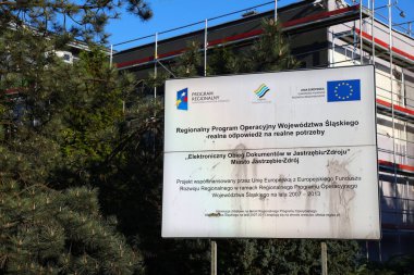 JASTRZEBIE ZDROJ, POLAND - 11 Mayıs 2021: Polonya 'nın Jastrzebie Zdroj kentindeki belediye binasının (Polonyaca: Urzad Miasta) önündeki Avrupa Bölgesel Kalkınma Fonu (ERDF) finansman panosu.