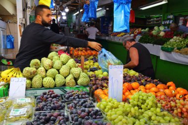 HAIFA, ISRAEL - 1 Kasım 2022: Satıcı, Hayfa, İsrail 'deki Talpiot Market' teki manavda meyve satıyor.