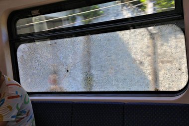 Damaged train window in Kuala Lumpur, Malaysia. Common public transportation vandalism problem in Malaysia. clipart