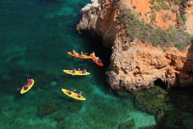 ALGARVE, PORTUGAL - 29 Mayıs 2018: Turistler Portekiz 'in Algarve bölgesindeki Lagos adalarında deniz kanosu macerasının tadını çıkarıyorlar. Algarve kıyı bölgesinde yılda 17 milyondan fazla turist ağırlanıyor..