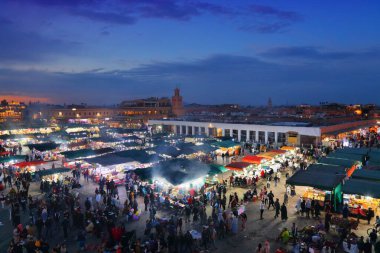 MARRAKESH, MOROCCO - 20 Şubat 2022: İnsanlar Marakeş 'in kare pazarı Jemaa el-Fnaa' yı (Djemaa el Fna) ziyaret ediyor. Meydan, UNESCO İnsanlığın Soyut Mirasının Başyapıtı olarak listelendi.