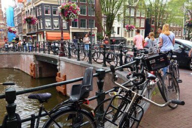 AMSTERDAM, NETHERLANDS - 8 Temmuz 2017: insanlar Amsterdam, Hollanda 'da Kloveniersburgwal kanalını geçer. Amsterdam Hollanda 'nın başkentidir..