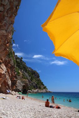 KONAVLE, CROATIA - 28 Haziran 2019: İnsanlar Hırvatistan 'ın Dalmaçya bölgesindeki Konavle bölgesindeki kayalıkların altındaki Pasjaca plajında tatil yapıyorlar.