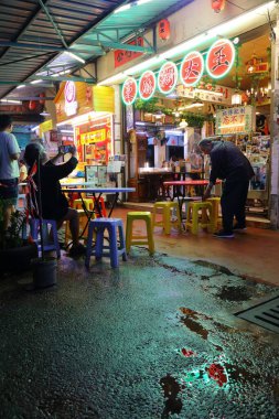 KUALA LUMPUR, MALAYSIA - 17 Mart 2024: Kuala Lumpur şehir merkezindeki yağmurlu bir gecede insanlar restoranı ziyaret ediyor.