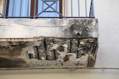 Weather damage of concrete. Flaking concrete on balcony in Siracuse city in Sicily, Italy. clipart