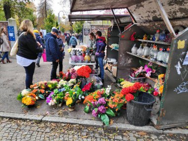 CHORZOW, POLAND - 1 Kasım 2023: İnsanlar Polonya 'da Azizler Günü' nde (Wszystkich Swietych) bir mezarlıktan mumlar ve yapay çiçek süslemeleri satın alıyorlar.