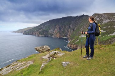 Kadın turist İrlanda 'nın Donegal ilçesinde bulutlu Slieve League uçurum manzarasının keyfini çıkarıyor.