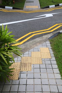 Singapur 'daki yaya geçidinde dokunmatik kaldırımlar (tenji blok). Görüş engelli altyapısını bozdu.
