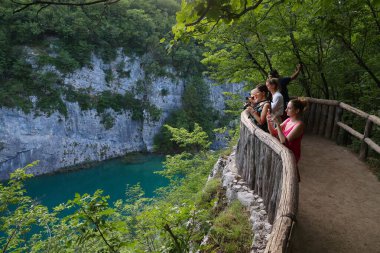 PLITVICE, CROATIA - 15 Haziran 2019: İnsanlar Hırvatistan 'daki Plitvice Lakes Ulusal Parkı' nı (Plitvicka Jezera) ziyaret ediyor. Plitvice, 2017 yılında 1,7 milyon ziyaretçiyle Hırvatistan 'ın en popüler ulusal parkı oldu..
