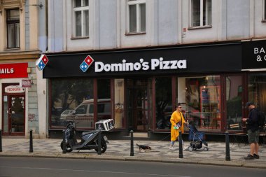 PRAG, CZECH REPUBLIC - 3 Mayıs 2024: İnsanlar Prag, Çek Cumhuriyeti 'nde Domino' nun Pizza zinciri fast food restoranının önünden yürüyorlar.