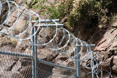 High fence and razor wire protection for government property in Gunnison County, Colorado. clipart