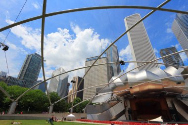 CHICAGO, USA - JUNE 27, 2013: People walk by Jay Pritzker Pavilion in Millennium Park in Chicago. Jay Pritzker Pavilion is a modernist bandshell designed by Frank Gehry. clipart