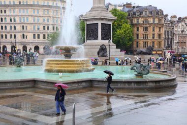 Londra 'da yağmurlu bir günde insanlar Trafalgar Meydanı' nı ziyaret eder. Meydan Westminster şehrinin bir parçasıdır ve 1840 'larda inşa edilmiştir..