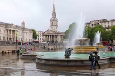 Londra 'da yağmurlu bir günde insanlar Trafalgar Meydanı' nı ziyaret eder. Meydan Westminster şehrinin bir parçasıdır ve 1840 'larda inşa edilmiştir..