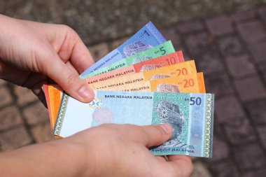 El ele tutuşarak Malezya usulü kağıt para. 1, 5, 10, 20 ve 50 halka banknotlar.