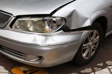 Ön tamponu hasarlı ve farları kırık klasik gümüş bir araba. Küçük bir kaza sonucu - Malezya 'da ufak bir trafik kazası.