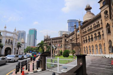 KUALA LUMPUR, MALAYSIA - 2 Mart 2024: İnsanlar Kuala Lumpur şehir merkezinde kalabalık caddenin ve KTM demiryolu işletme binasının eski mimarisinin yanında yürüyor.