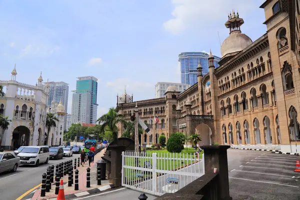 KUALA LUMPUR, MALAYSIA - 2 Mart 2024: İnsanlar Kuala Lumpur şehir merkezinde kalabalık caddenin ve KTM demiryolu işletme binasının eski mimarisinin yanında yürüyor.