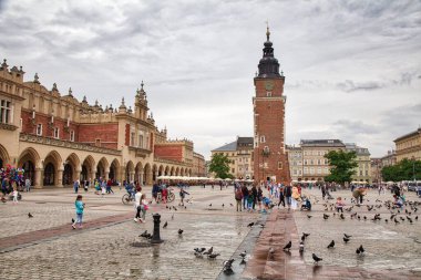 KRAKOW, POLAND - 3 Temmuz 2021: İnsanlar Krakow, Polonya 'da yağmurlu bir günde Rynek Meydanı' nı ziyaret ediyor. Krakow Tarihi Merkezi UNESCO 'nun Dünya Mirasları Alanıdır..