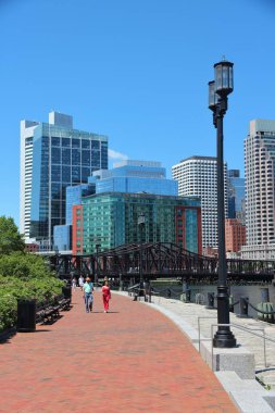 BOSTON, ABD - 9 Haziran 2013: İnsanlar güneşli bir yaz gününde Boston ufuk çizgisi manzaralı Güney Boston liman yürüyüşünü ziyaret ederler.