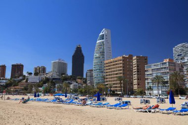 BENIDORM, İspanya - 9 Nisan 2025: İnsanlar güneşli bir günde İspanya 'nın Benidorm kentindeki Poniente plajında vakit geçirirler.