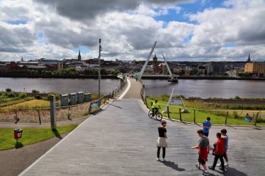 DERRY, İngiltere - 24 Haziran 2024: Yayalar Kuzey İrlanda 'da Derry' deki Barış Köprüsü 'ndeki Foyle nehrini geçtiler.