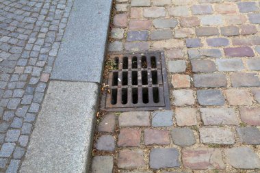 Yol kenarındaki yağmur suyu drenajı demir metal ızgara yaptı. Çek Cumhuriyeti Prag kentsel altyapısı. Eski kaldırım taşı kaldırımı.