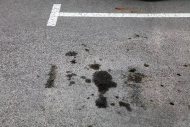 İspanya 'da park yerindeki yağ lekeleri. Toprak kirliliği sorunu. Asfalt yüzeyinde motor yağı lekeleri.