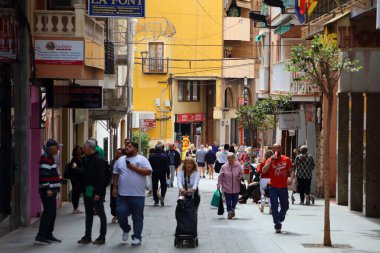 BENIDORM, İspanya - 11 Nisan 2025: Valensiya Topluluğu 'ndaki Benidorm tatil köyünde insanlar alışveriş caddesi boyunca yürüyor.