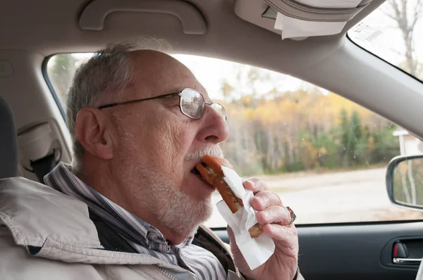 Senior Mand Med Udtryksfulde Ansigt Spiser Fastfood Pommes Frites Hotdogs - Stock-foto